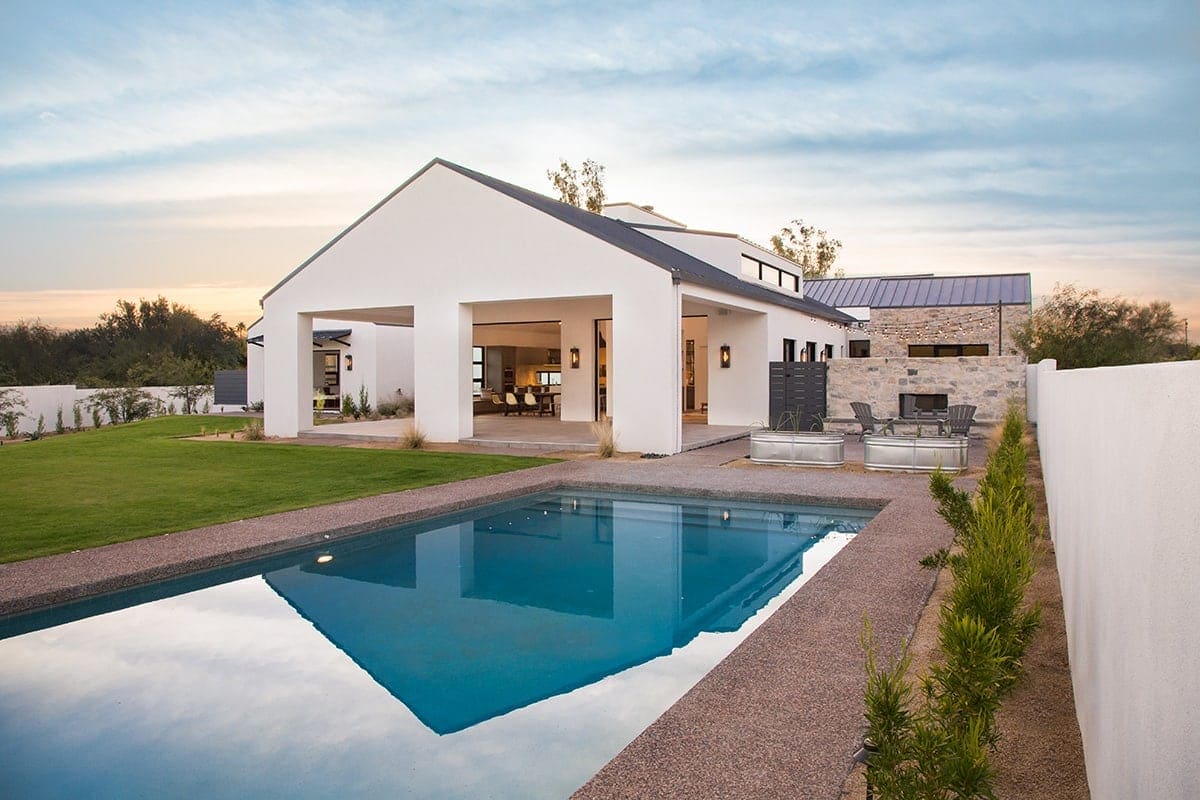 Contemporary house with swimming pool and landscaped garden at sunset.