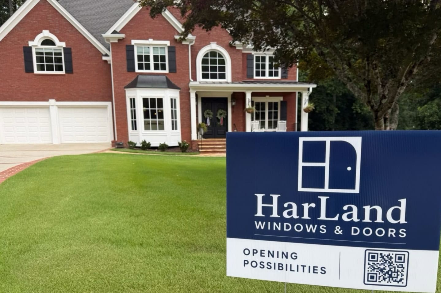 Photo of a beautiful home with a HarLand Windows and Doors sign in the yard.